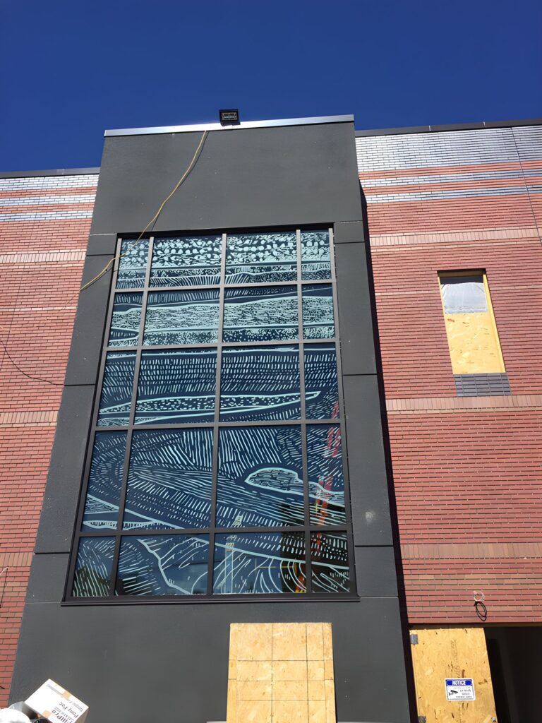 Tall curtain wall window installation on a brick building