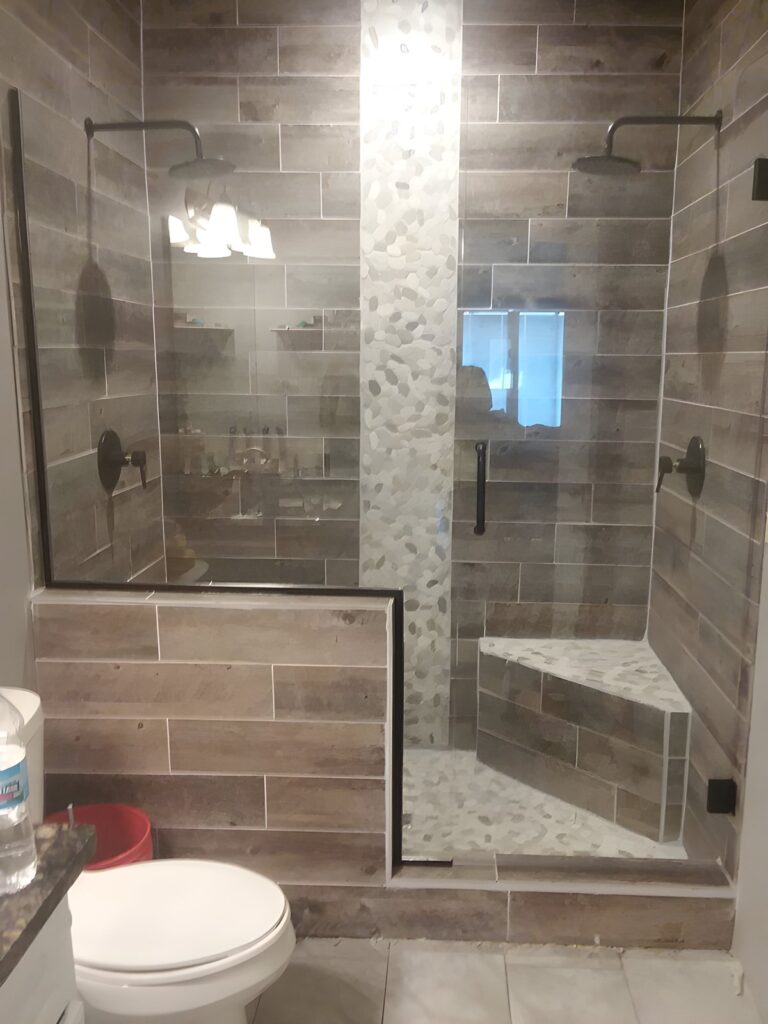 Glass shower enclosure with half wall and bench